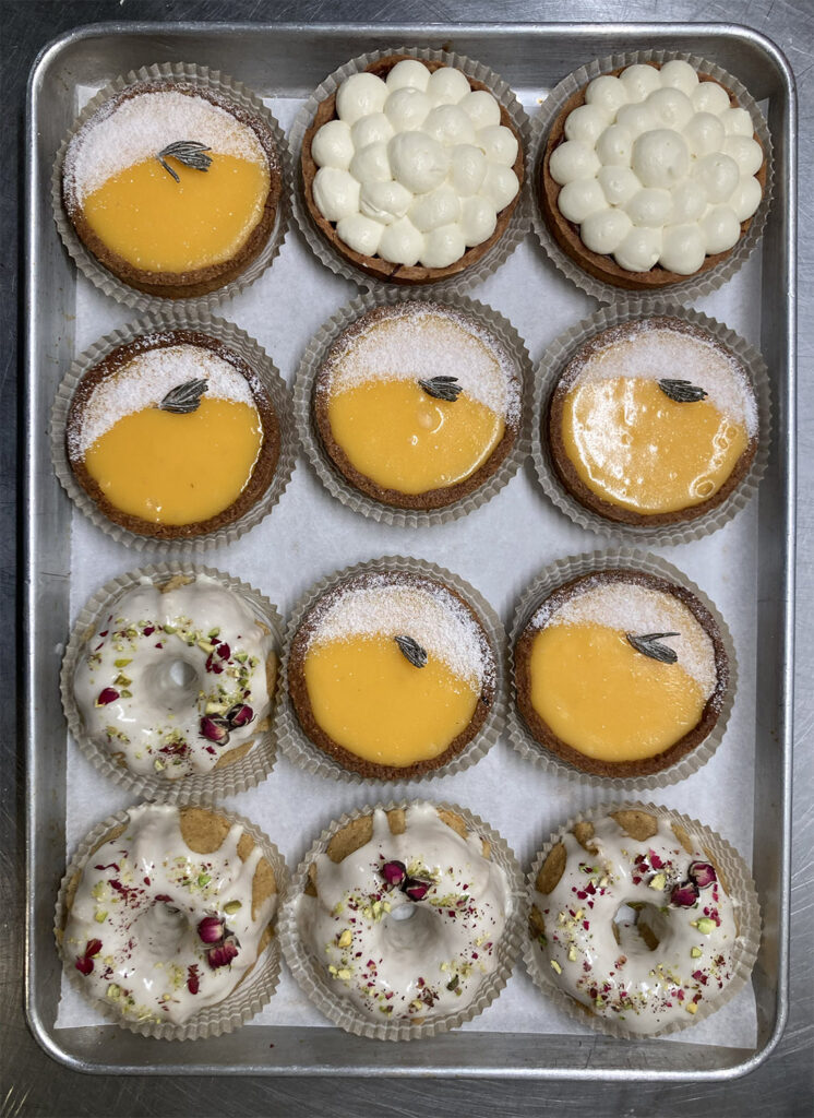 A picture of a tray of assorted tarts, including chocolate creme puff, lemon, and Persian love cake.